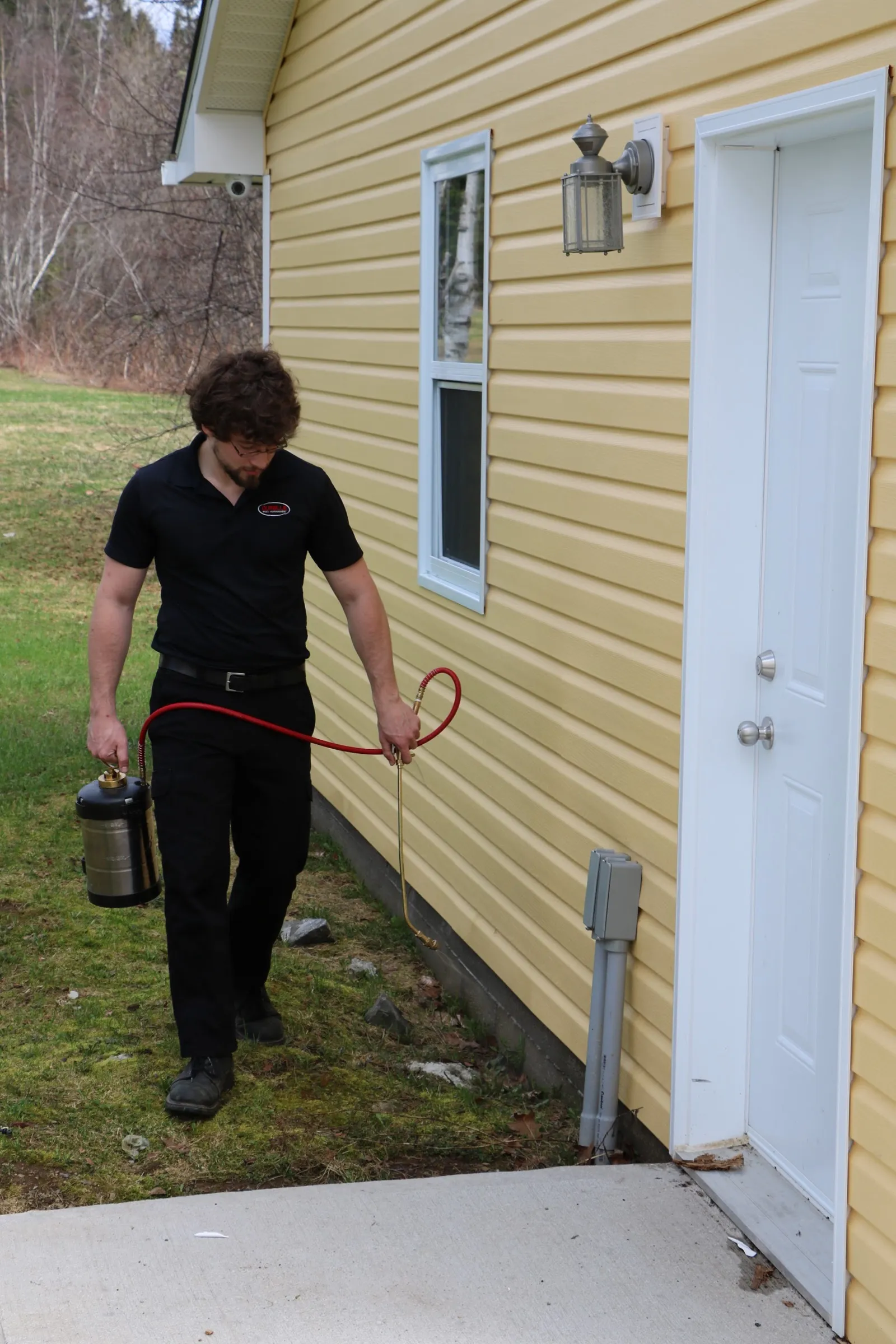 Durelle technician applying an exterior perimeter treatment along a home foundation